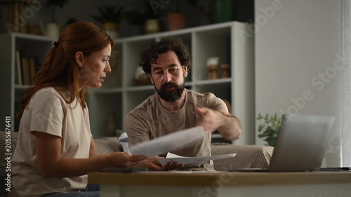 Stressed couple arguing over bills and finances at home. Frustrated man and woman discussing debt and budget problems