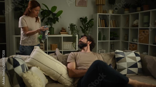 Angry wife shouting at her husband using a smartphone while ignoring household chores and her requests
