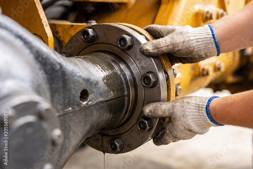 Foto Mechanic wearing gloves tightens bolts on heavy machinery axle assembly