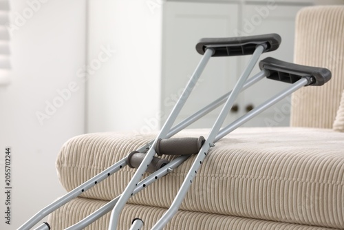Obraz na plátne Metal axillary crutches near sofa indoors, closeup. Mobility aid
