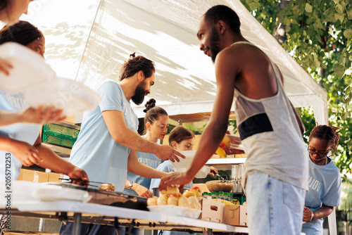 Canvastavla Multicultural team of charity workers serving food to refugees at outdoor nonprofit programme