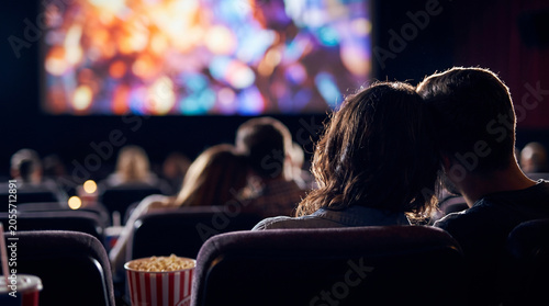 Young couple enjoying movie premiere at cinema auditorium during romantic date