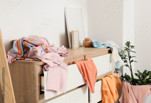 Photos Messy clothes on wooden dresser with open drawers, household disorganization and