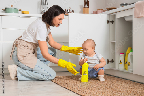 Photos Mother protecting baby from household cleaning chemicals, child safety and POISO