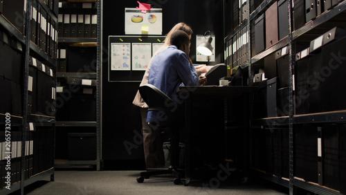 Foto Dedicated private investigators discuss the case and do extensive investigation to solve crime in room crammed with papers and evidence