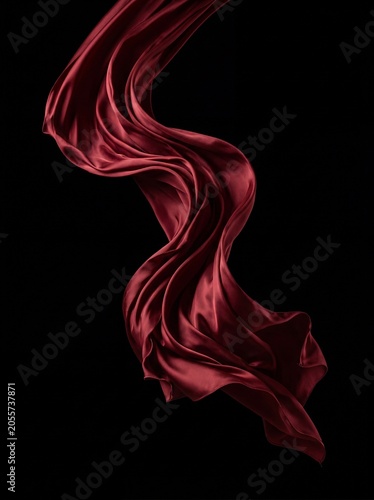 Elegant red silk fabric flowing gracefully against a solid black background
