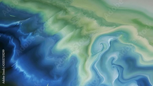 Abstract blue and green liquid paint mixing and swirling in a hypnotic fluid motion background creating a colorful texture