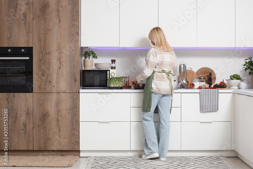 Blonde woman in apron cooki...