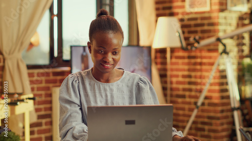 Fotografie African American person writing blog at home office, catching sunset light while finishing daily activites