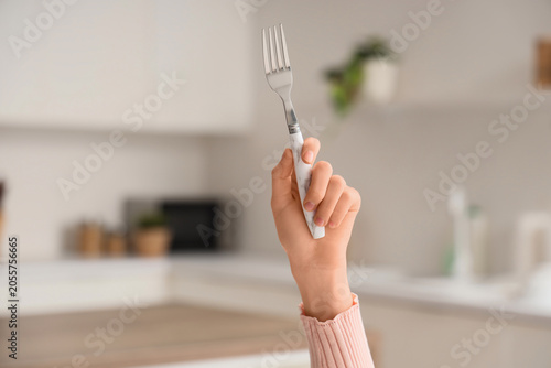 Fotografie Childs hand holding a silver fork with marble handle in a modern kitchen setting