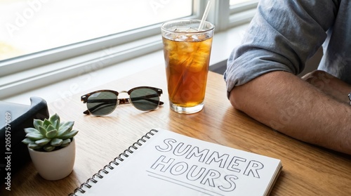Summer hours concept with notebook on desk, iced tea and sunglasses for flexible work schedule planning and seasonal business strategy
