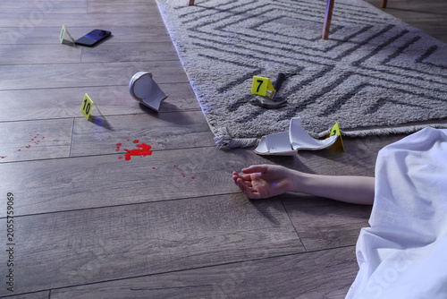 Obraz na płótnie Crime scene investigation with blood splatter, broken objects, and victims arm o