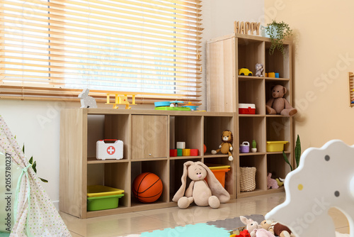 Tableau sur toile Childrens playroom interior with wooden storage shelves, assorted toys, and brig