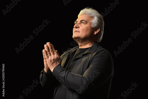 Senior man praying with cla...