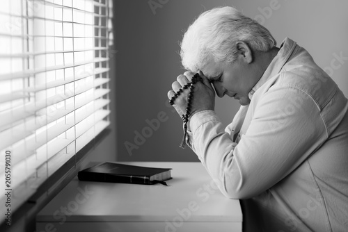 Elderly man praying with ro...