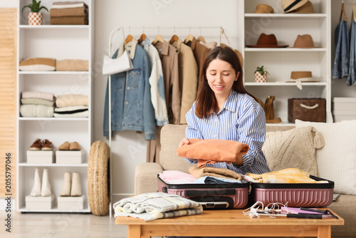 Young woman packing suitcas...
