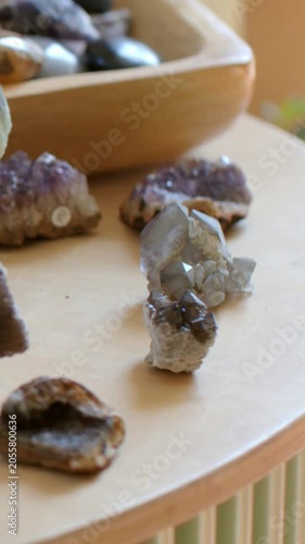 Vertical video: Panning camera focusing on quartz and druzy on wood table, revealing amethyst, bowl