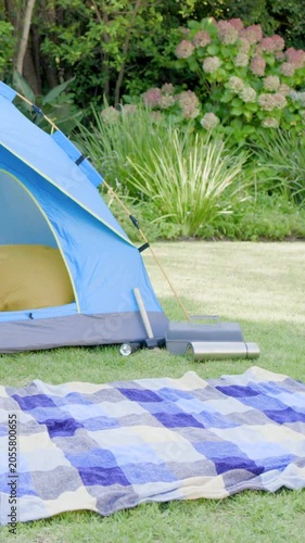 Vertical video: Panning camera in yard revealing tent opening and cushion for detail, copy space