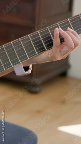 Vertical video: Recording as camera focusing, left hand practicing chords on guitar in bedroom