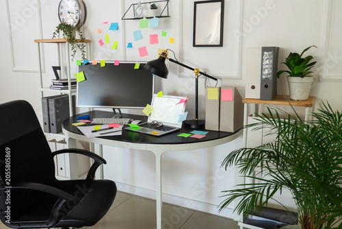 Interior of light office with workplace, shelf units and sticky notes
