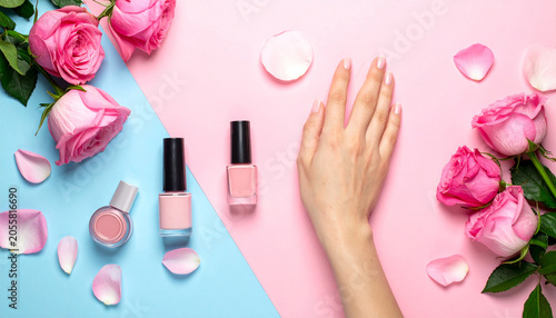 Nail Care and Rose Elegance: A manicured hand showcases perfectly polished nails, surrounded by delicate pink rose petals and bottles of nail polish, set against a pastel pink and blue backdrop.