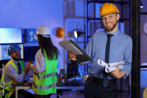 Male engineer working with clipboard in office at night