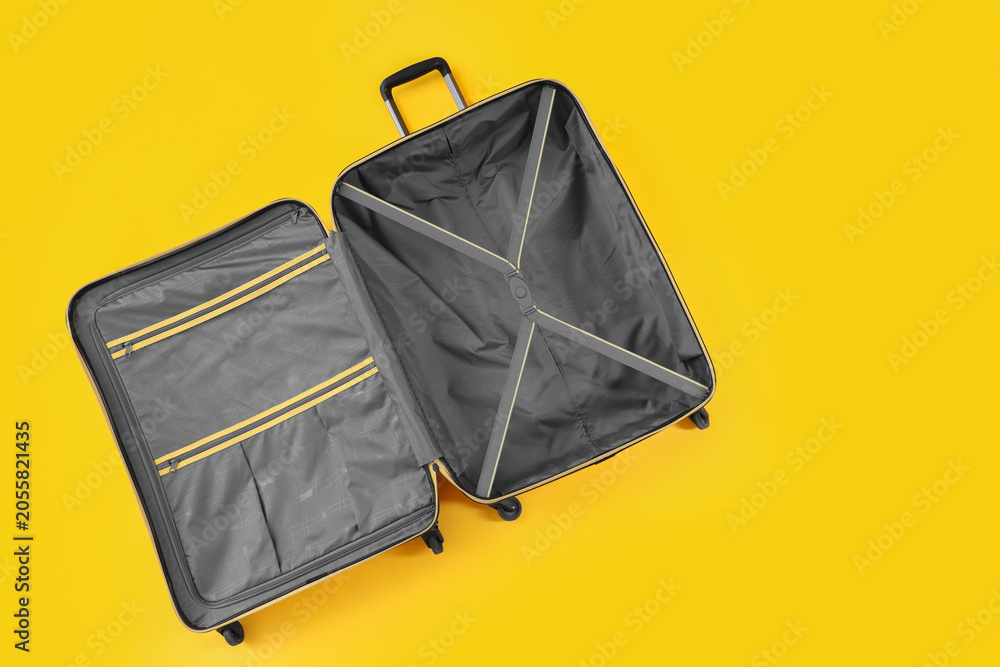 Naklejka premium Open suitcase on yellow background, top view
