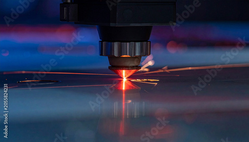 Laser Cutting Precision: A close-up view of a high-tech laser cutter meticulously engraving a metal surface, with brilliant red light and scattered sparks illuminating the industrial process.