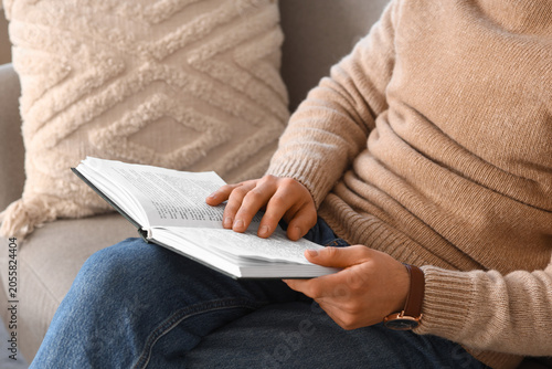 Young man reading book on g...