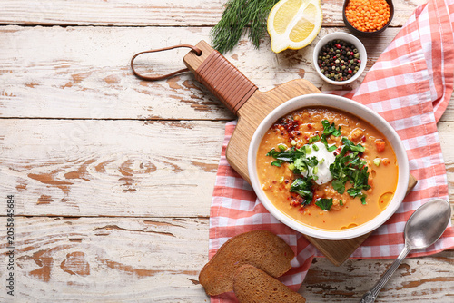 Bild auf Leinwand Bowl of tasty lentil soup with parsley and sour cream on white wooden background