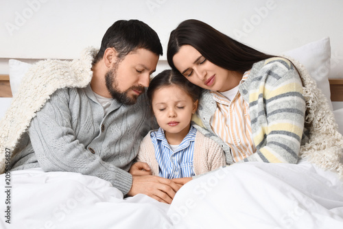 Frozen family under blankets with lack of heating in bedroom