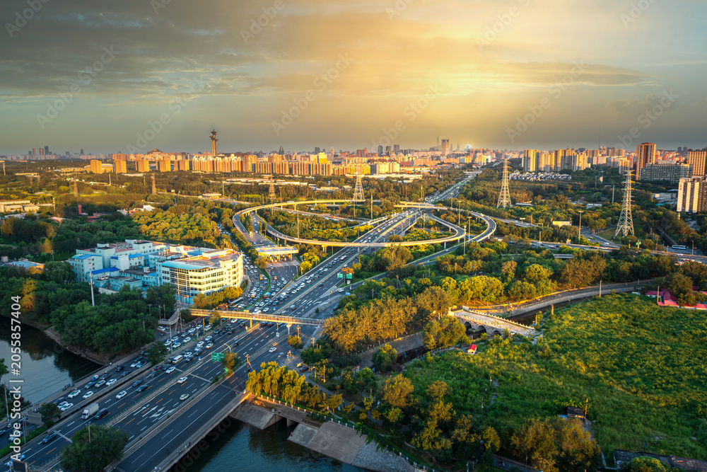 Obraz premium A panoramic aerial view of Beijing's multi-level transportation system and ecological livability under the golden sunset.