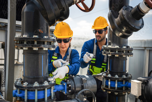 Team of engineers inspecting cooling equipment and water pump at industrial plant, Professional technician and worker performing maintenance on industrial HVAC and piping system on commercial rooftop