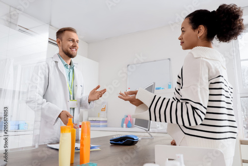 Pharmacist consulting female customer at pharmacy counter, healthcare profess...
