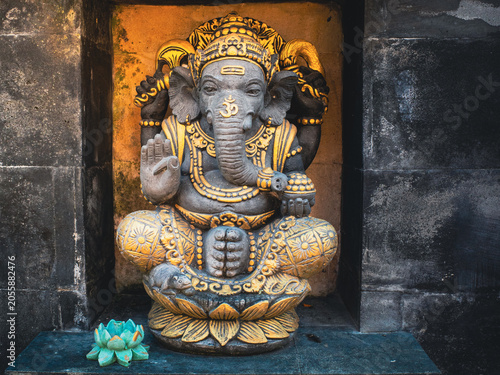 Ganesha, the revered Hindu elephant god, sitting adorned in dark stone with intricate golden details, blessing and symbolizing wisdom, prosperity, and the removal of obstacles
