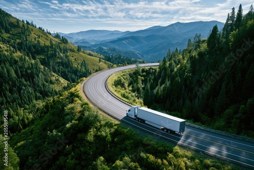 White semi-truck navigates a winding road through a lush, green mountain landscape