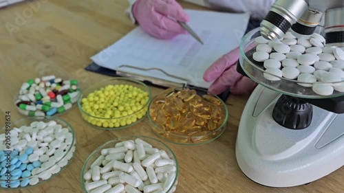 Research on pills is conducted using a microscope in a laboratory setting in the afternoon