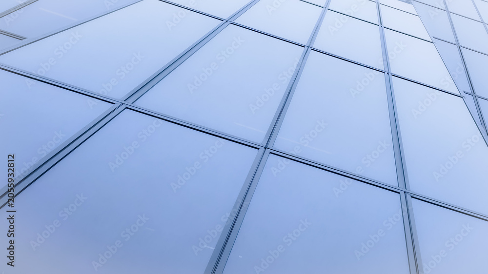 Fototapeta premium Modern corporate skyscraper glass facade with geometric window panels and clean linear architecture pattern