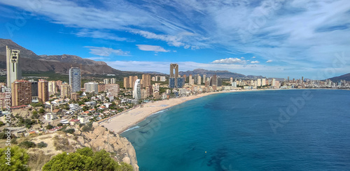 Panoramic view of Benidorm city skyline with long sandy beach resort buildings skyscrapers and mountains near blue sea