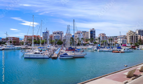 Scenic view of Gandia marina harbor with luxury motor yachts sailboats and residential buildings