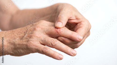 Close-up of a senior woman's hands massaging a painful and swollen finger joint, indicating arthritis or inflammation.