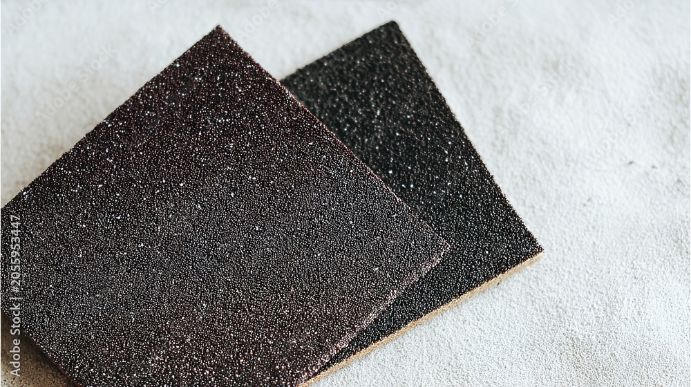 Fototapeta premium sandpaper. A sheet of sandpaper with dark granules next to a piece of polished metal. safety posters, maintenance manuals, designed for industrial assembly lines and welding operations.