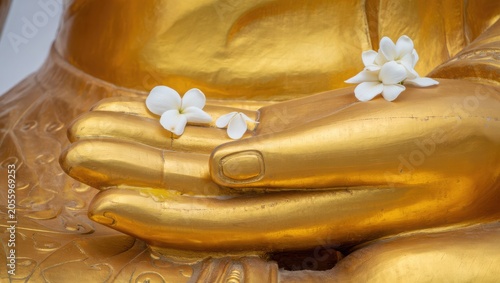 Buddha Hands Holding White Jasmine Flowers in Golden Statue Close-Up