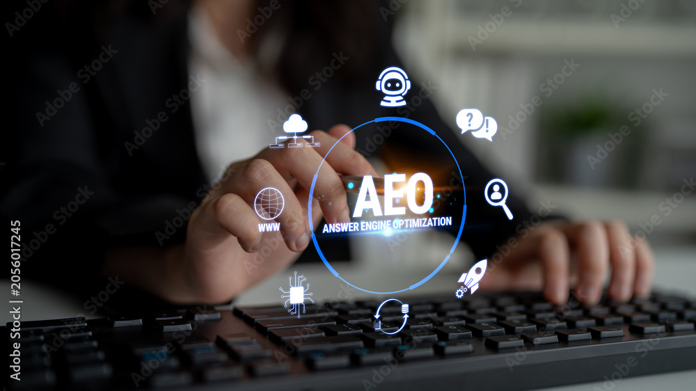 Obraz premium Hand Operating Keyboard with AEO Graphic Overlay for Answer Engine Optimization in Modern Business Environment Fluxor.