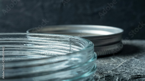 Macro linear composition of precision-molded glass jar threads. Raking light emphasizes cooling lines and mineral texture on raw slate, offering extensive copy space.