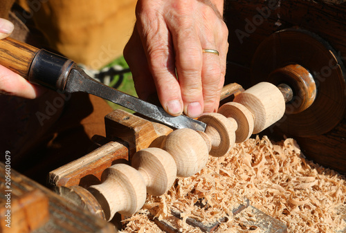 experienced artisan working wood block using old fashioned turning equipment and sharp chisel