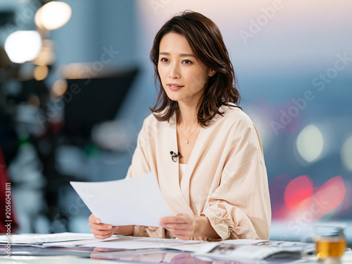 Woman News Anchor Reading Script at Studio Desk