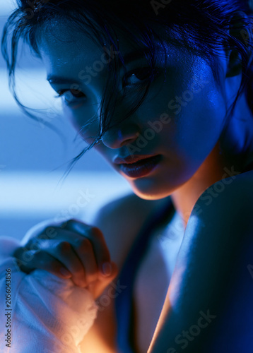 Woman Boxer Holding Wrapped Hands in Blue Light