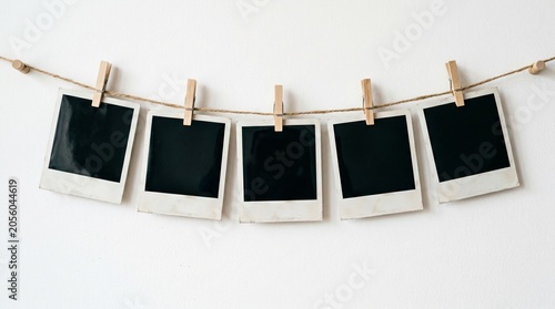Five blank polaroid photos hanging on a string with clothespins