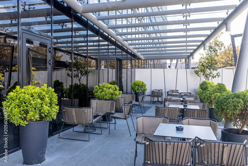 Modern outdoor restaurant terrace with stylish chairs tables and green plants
